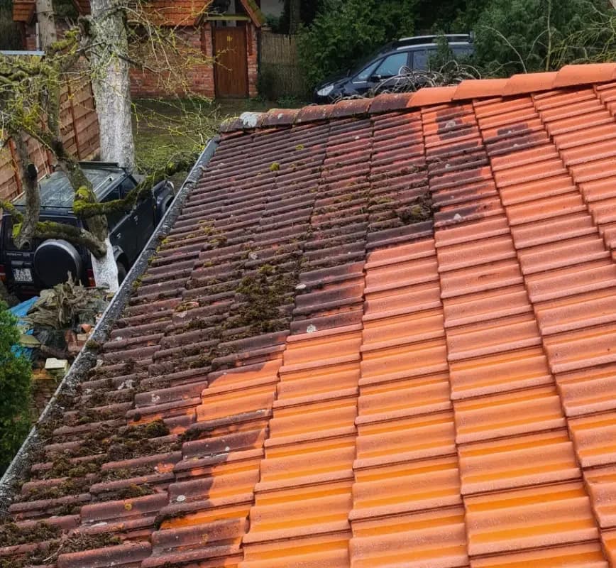 Dach w trakcie mycia: lewa część ciemna i porośnięta mchem, prawa już czysta i pomarańczowa